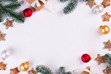 Noel ve Yeni Yıl bayramı kompozisyonu. Çerçeveyi köknar dallarıyla, hediye kutusuyla, beyaz arka planda top ve yıldızlarla süsleyin. Düz konum, üst manzara şenlik konsepti.