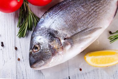 Baharatlı ve limonlu taze deniz balığı pişirmeye hazır. Dorado ya da ahşap arka planda çipura balığı. Düz yatıyordu