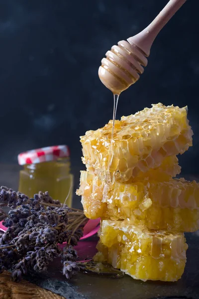 Pente de mel com flores de lavanda - comida doce em fundo escuro — Fotografia de Stock