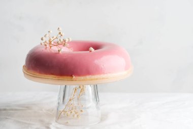 Açık gri arka planda cam bir tabakta taze pişmiş ev yapımı çilek jöleli pembe tatlı..