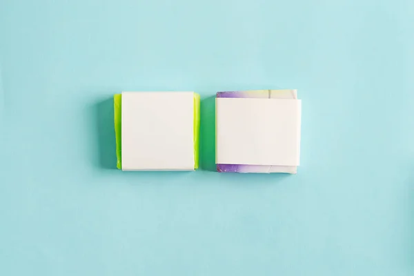 Dva ručně vyrobené mýdlo zábal box mock-up balíček s barevným bar mýdlo izolované na modrém pozadí — Stock fotografie