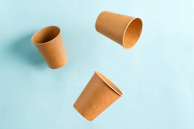 Pastel mavi arka planda uçan tek kullanımlık kağıt bardaklar. Sıfır Atık