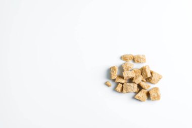 Beyaz arkaplanda doğal kamış esmer şeker küpleri.