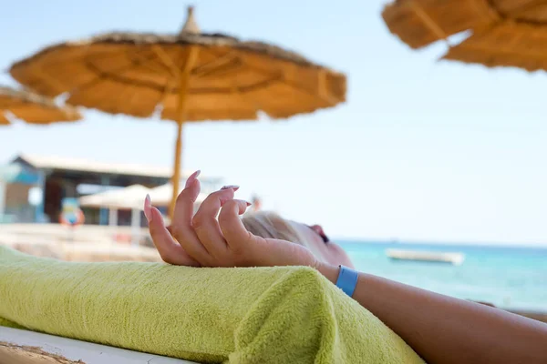 Mão das mulheres com manicure e pulseira azul relaxar em uma praia — Fotografia de Stock
