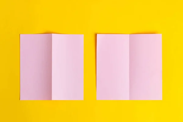 Folletos de papel rosa con forma de bifold sobre fondo amarillo. — Foto de Stock