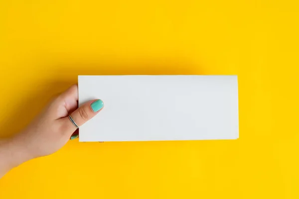 Λευκό προσπέκτους χαρτί σε ένα γυναικείο χέρι. — Φωτογραφία Αρχείου