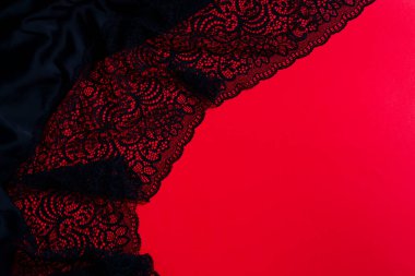 Kırmızı arka planda siyah dantel kumaşlı yaratıcı dekoratif zemin, kopyalama alanı. Üst Manzara. Kara Cuma Satışı konsepti.