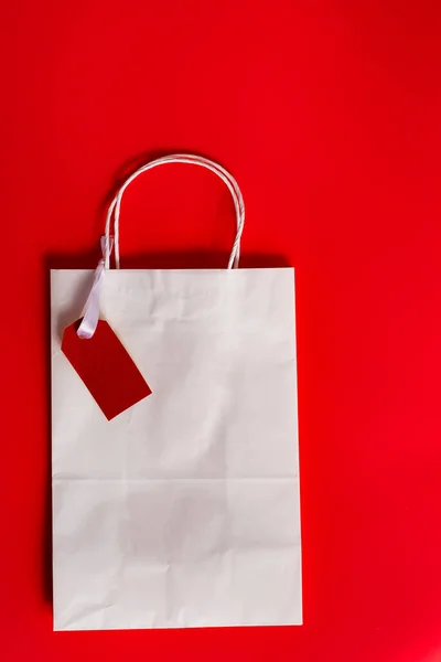 在红色背景上贴有服装标签的购物袋 复制空间 顶部视图 黑色星期五发售概念 — 图库照片