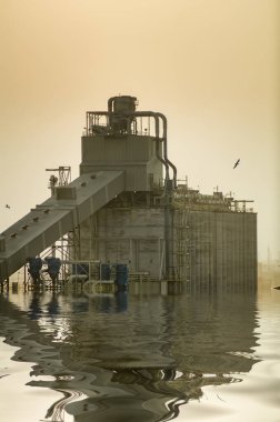Sel basmış bir sahil endüstriyel kompleksinin grafiksel olarak yenilenmiş görüntüsü, iklim değişikliğinin olası bir sonucunu göstermektedir.