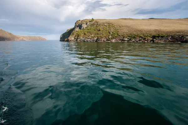 Turquoise water of Lake Baikal with a rock. Taken from the ship. There is a strait between the rocks.