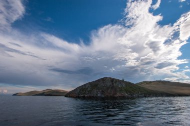 Baykal Gölü'ndeki bulutlarda serin gökyüzünün arka planında tepeler. Sudan bak. Su dalgalanmaları üzerinde.