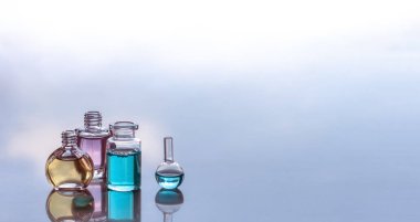 Yansımaları ile aromatik yağlar dört şişe. Sarı, pembe, mavi renk. Mavi bulanık arka plan. Metin için yer.