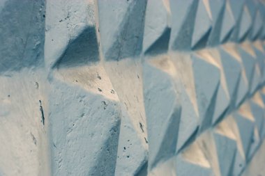 Soyut grunge arkaplanı. Uzağa uzanan bir piramidin somut geometrik figürleri. Betonda ve boyada düzensizlikler var. Maviyle boyanmış. Başlangıçta seçici odak.