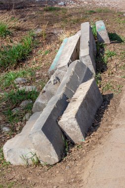 Yol kenarındaki çimlerin üzerinde birkaç eski kaldırım taşı var. Yerde beton kaldırımlar var. Tabaklardaki eski toprak. Dikey.