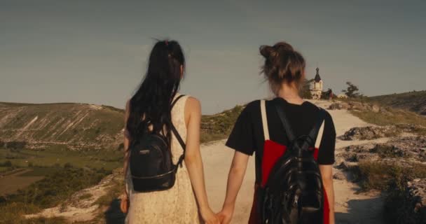 Jeune couple féminin marchant en tenant la main . — Video