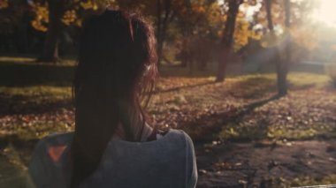 Güzel bir sonbahar gününde bankta dinleyen kadın.