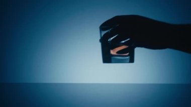 Mavi bir arka plan üzerinde yansıtıcı bir yüzeye bir bardak viski alıp almak