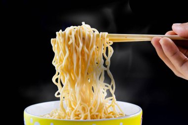 Çubuk yemek çubuğu, buharlı erişte ve siyah arka planda bir kasede duman kullanarak. Manzara, masada Asya yemekleri, yemek konsepti.