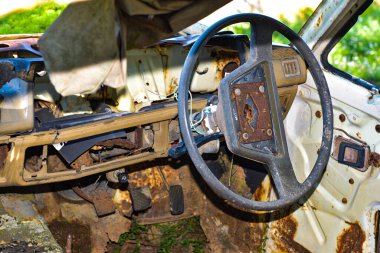 Direksiyon ve gösterge paneli olan eski arabanın içi, otoyolun kenarındaki paslı bir kamyonun içindeki direksiyon simidi..