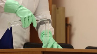 Laboratuvar bilim adamı laboratuvar şişesine sıvı döküyor. Laboratuvar deneyi yapan kadın bilim adamına yakın çekim. Laboratuvar çalışanları deney kabında kimyasal sıvıyla laboratuvar testleri yapıyor.