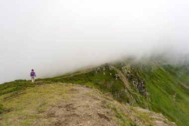 Genç bayan yürüyüşçü yürüyüş gezisinde güzel dağlarda oturur. Doğada dinlenen aktif bir insan. Kamp yapan sırt çantalı gezgin etkinleştirildi