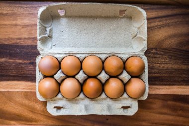 Ahşap mutfak masasında yumurta tepsisindeki çiğ yumurtalar.