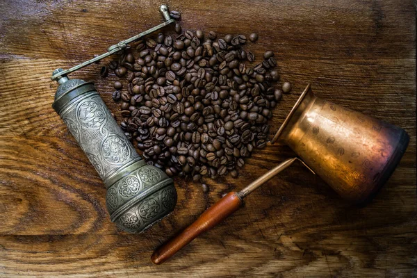 Turkish coffee concept. Copper coffee pot (Cezve), vintage coffee grinder, cup, coffee beans on a dark wooden background. Top view. horizontal.