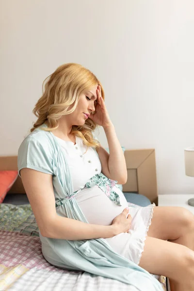 Hamile Bir Kadın Yatakta Oturmuş Baş Ağrısı Çekiyor — Stok fotoğraf