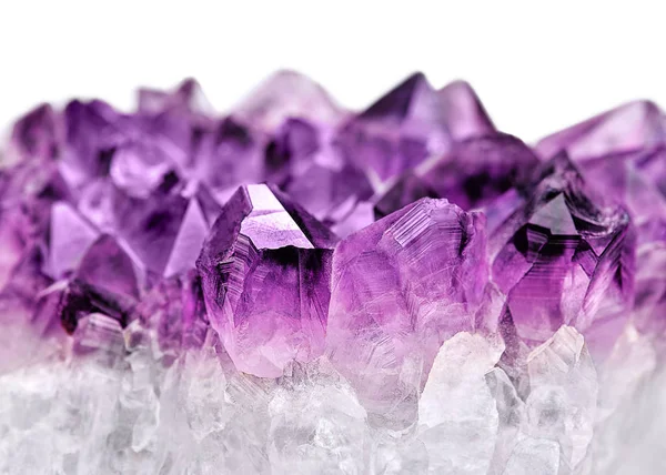 Crystal taş makro mineral küçük alan derinliği ile. Beyaz arka plan üzerinde mor kaba ametist kuvars kristalleri