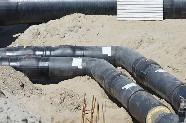 metal pipes with insulation underneath the road on the construction