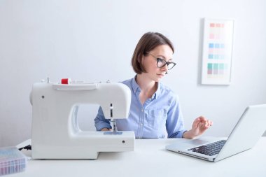 Terzi giysi ekipmanları ile masaüstünde oturan ve dizüstü bilgisayardan bilgi analiz