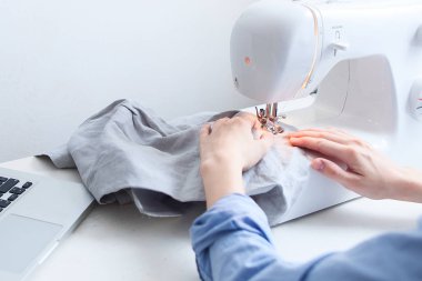 Terzi giysi ekipmanları ile masaüstünde oturan ve dizüstü bilgisayardan bilgi analiz