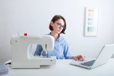 Terzi giysi ekipmanları ile masaüstünde oturan ve dizüstü bilgisayardan bilgi analiz