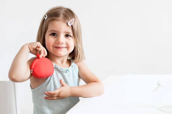 Toddler girl with red wallet,purse play with coins at home — Stock Photo, Image