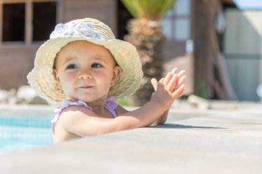 Yüzme havuzunda şapkalı kız bebek alkışlıyor