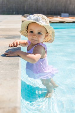 Yüzme havuzunda şapkalı kız bebek kamera bakmak.
