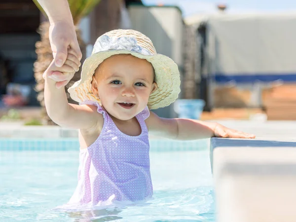 Baby girl with hat in swimming pool and mother. — Stock Photo, Image