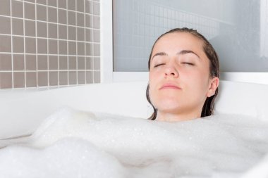 Beyaz kız köpüklü bir küvet içinde rahat