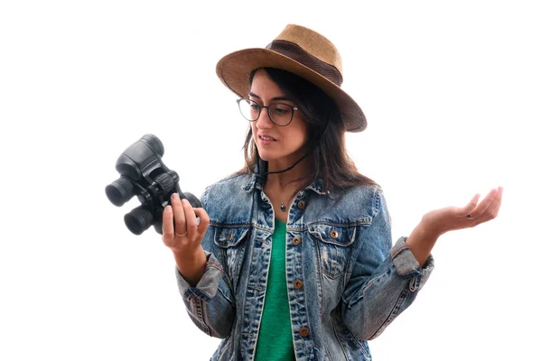 Brunette Scout meisje met bril gekleed in denim jasje en hoed, met gedesoriënteerde verrekijker, weet niet hoe te gebruiken — Stockfoto