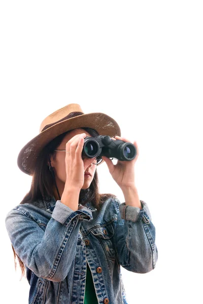 Brünettes Pfadfindermädchen mit Brille in Jeansjacke und Hut, mit Fernglas überrascht isoliert — Stockfoto