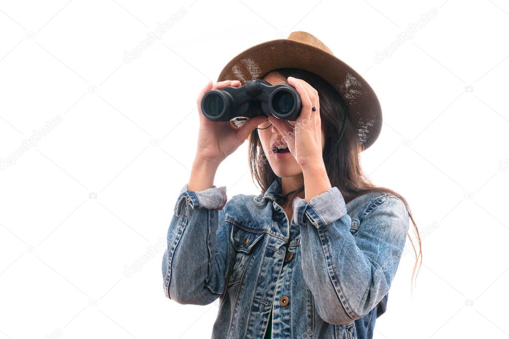brunette scout girl with glasses dressed in denim jacket and hat, with binoculars surprised isolated