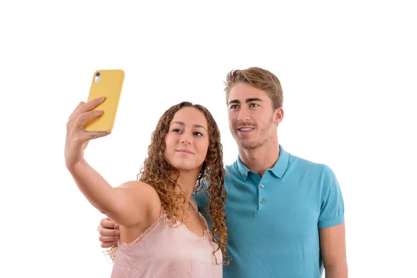 Młody kaukaski para lub bracia Robienie selfie wraz z żółtym telefonem komórkowym, chłopiec ubrany w niebieską koszulę i różowe dziewczyny w białym tle na wyizolowanym — Zdjęcie stockowe