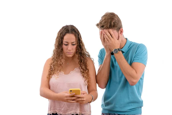 Jonge Kaukasische paar of broers ontvangen slecht nieuws op hun mobiele telefoon op zoek bezorgd of geschokt in witte achtergrond geïsoleerd, jongen gekleed in blauw shirt en roze meisje — Stockfoto