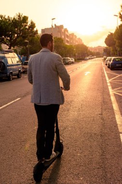 turuncu renklerle gün batımında bir yolda bir elektrikli scooter sürüş yetişkin latin adam