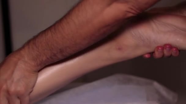 Fußmassage im Massageraum. Ein professioneller Masseur massiert den Wadenmuskel. Entspannung, Wellness-Massage, Therapie
