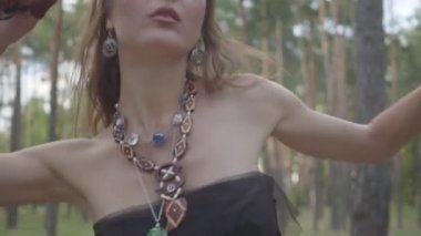 Ağaçların altında dans başında dalları bir çelenk ile çekici bir dryad veya orman peri portresi. Orman yaratığının eski ritüeli. Ormanda dansçı performansı