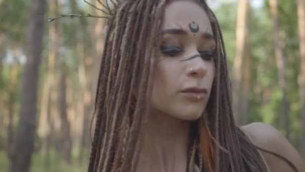 Atractiva dríada o hada del bosque con trenzas afro y tatuajes en el cuerpo bailando con un hermoso disfraz. El antiguo ritual de la criatura del bosque. Rendimiento de la bailarina en el bosque — Vídeos de Stock