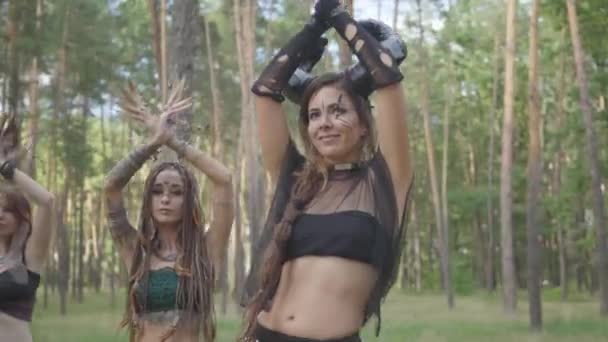 Опытные молодые женщины в театральных костюмах лесных нимф танцуют в лесу, демонстрируя перфоманс или совершая ритуал — стоковое видео