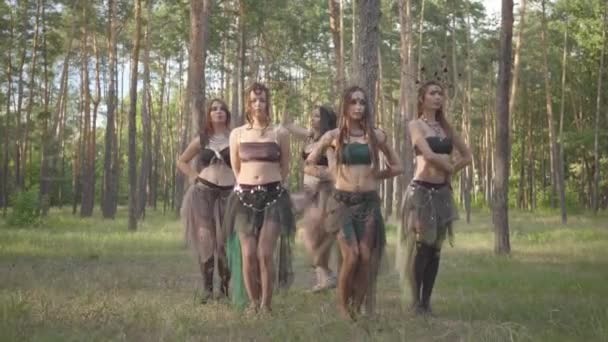 Young women in theatrical costumes of forest dwellers or devils dancing in forest showing perfomance or making ritual — Stock Video