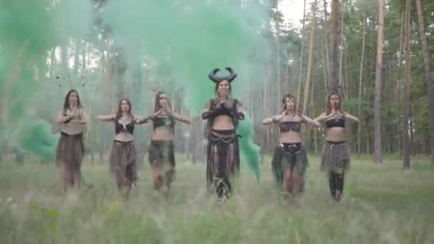 Csoport női táncosok a make-up és a misztikus mesés jelmezek táncoló színes füst. Erdei tündérek, driádok szórakozni a fák között. A szabadtéri táncosok teljesítménye.